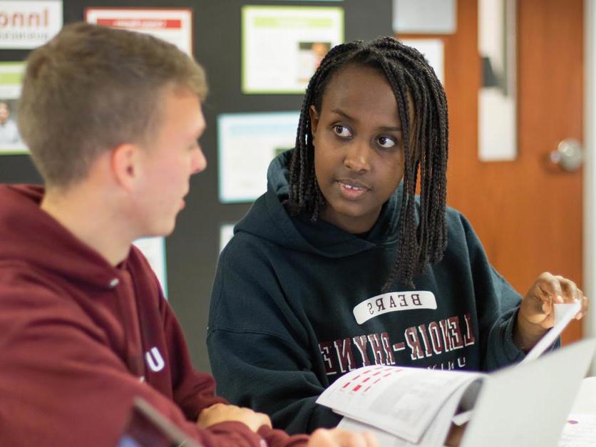 Two students talking while working in classroom on class assignment